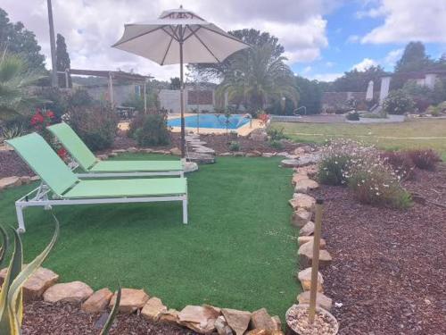 a green chair and an umbrella in a yard at Quinta Cunte - Casa Girassol in São Luis