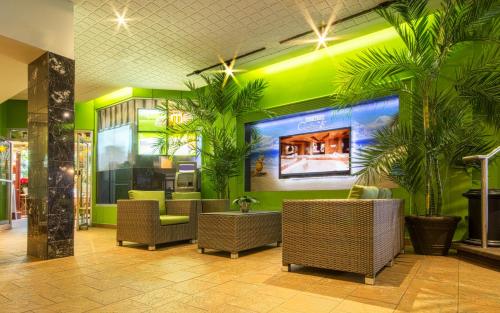 a restaurant with green walls and palm trees and chairs at Hôtel Québec Inn in Quebec City