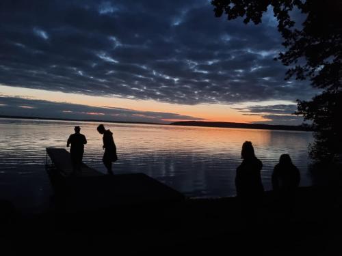 a group of people standing near the water at sunset at Zum Waldblick in Funfseen