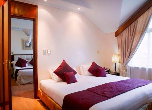 a bedroom with a large bed with red pillows at Boma Inn Nairobi in Nairobi