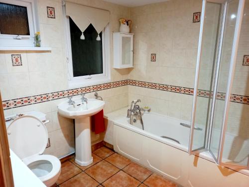y baño con aseo, bañera y lavamanos. en Luxurious Entire Studio in Axminster suitable for en Axminster