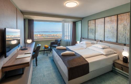 Pokój hotelowy z łóżkiem, biurkiem i telewizorem w obiekcie Hunguest Hotel Bál Resort w mieście Balatonalmádi