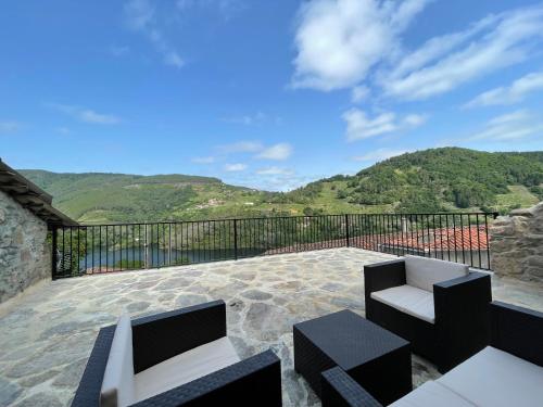 a patio with two chairs and a balcony with mountains at Ecolagar O Barqueiro in Pantón
