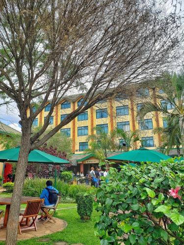 a building with people sitting at tables in front of a building at Boma Inn Nairobi in Nairobi