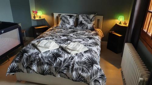 un letto con piumone e cuscini in bianco e nero di Maison, jardin, barbecue et vélo classé 3 étoiles a Dives-sur-Mer