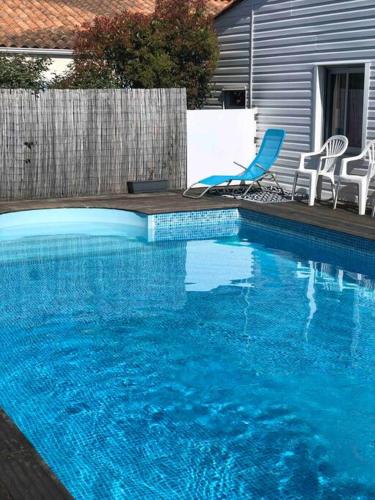 une piscine bleue avec deux chaises et une clôture dans l'établissement L’étoile de mer , maison en plein centre ville, à Bretignolles-sur-Mer