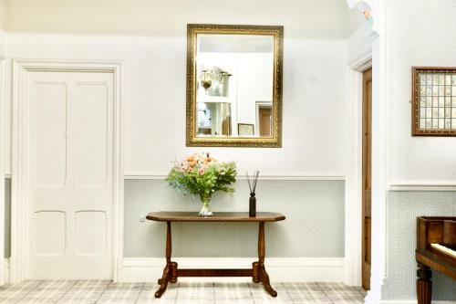 a vase of flowers on a table with a mirror at The Buckley Arms in Dinas Mawddwy