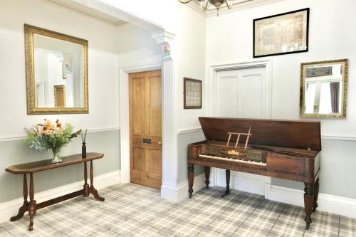 a piano in a room with a table and a mirror at The Buckley Arms in Dinas Mawddwy