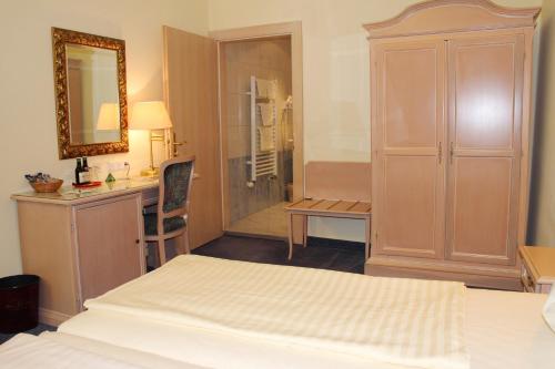 a bedroom with a bed and a desk and a mirror at Altstadt Hotel Mosser Villach mit Parkplatz in Villach
