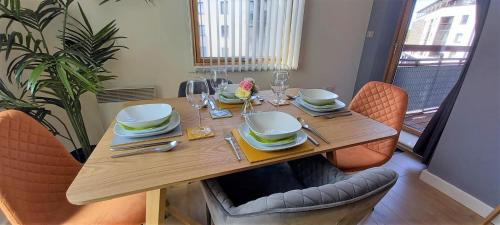 a wooden table with chairs and plates and glasses at Stunning Modern Coventry City Centre Apartment in Coventry