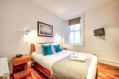 um quarto com 2 camas com almofadas azuis e uma televisão em Sumptuous 2BR Apt Next To Edinburgh Castle! em Edimburgo