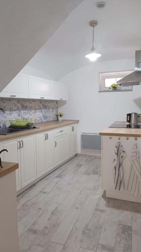a kitchen with white cabinets and a wooden floor at Penzion HARMONIE in Trhové Sviny