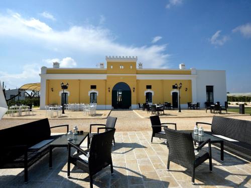 a yellow building with tables and chairs in front of it at Tenuta Orsanese in Ginosa Marina