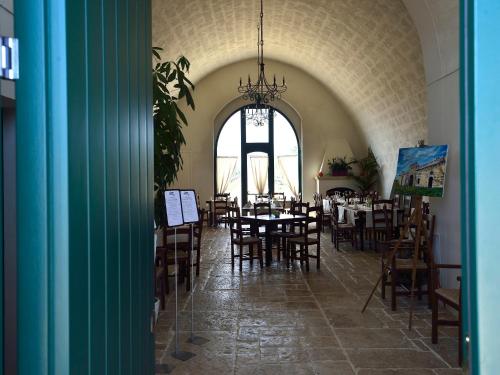 a dining room with tables and chairs and a large window at Tenuta Orsanese in Ginosa Marina