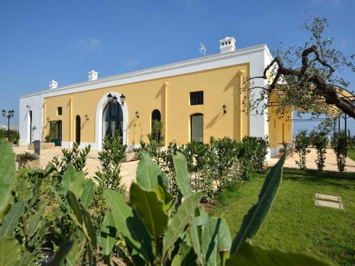 a yellow and white building with plants in the foreground at Tenuta Orsanese in Ginosa Marina