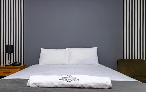 a bed with a white blanket on top of it at Hotel Taurus in Piura
