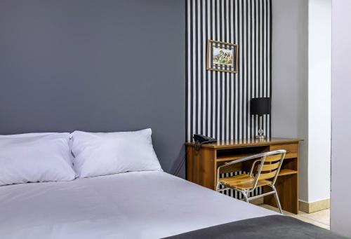 a bedroom with a bed and a desk with a chair at Hotel Taurus in Piura