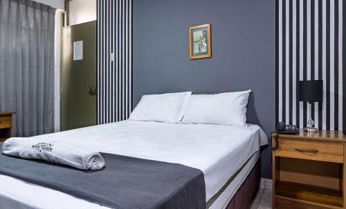 a bedroom with a large bed with white sheets and a table at Hotel Taurus in Piura