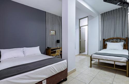 a bedroom with two beds and a chair in it at Hotel Taurus in Piura