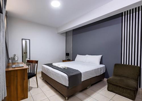 a bedroom with a bed and a chair and a desk at Hotel Taurus in Piura