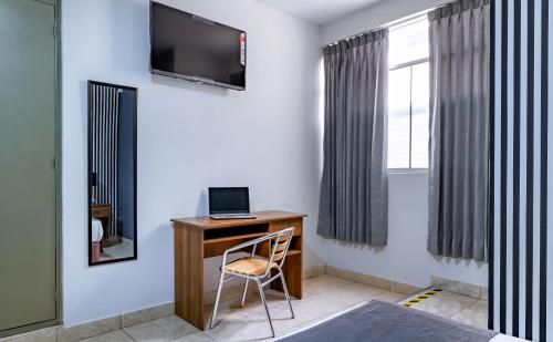 a room with a desk with a laptop and a window at Hotel Taurus in Piura
