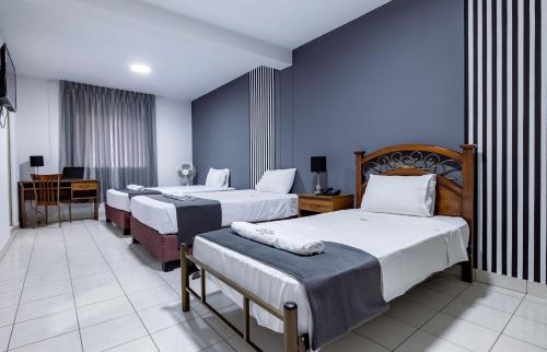 a hotel room with three beds and a desk at Hotel Taurus in Piura