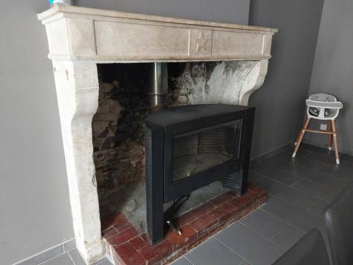 a stone fireplace in a room with a stool at La Ribote in Sancerre