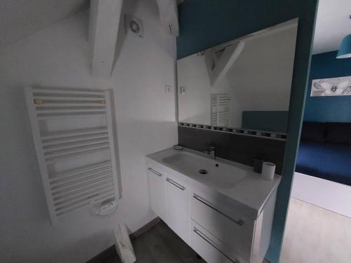 a white bathroom with a sink and a mirror at La Ribote in Sancerre