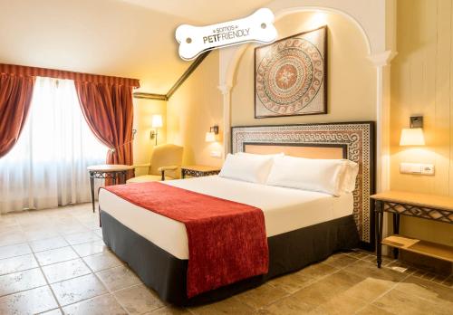 a hotel room with a bed with a red blanket at Hotel Ilunion Mérida Palace in Merida