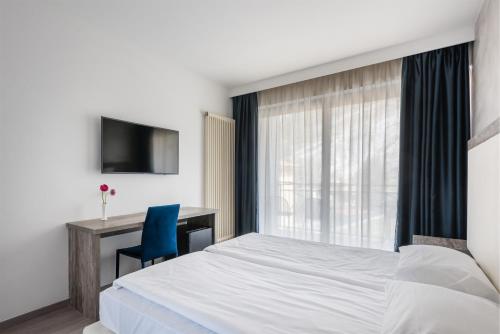 a bedroom with a bed and a desk and a window at Hotel De Nac in Nago-Torbole