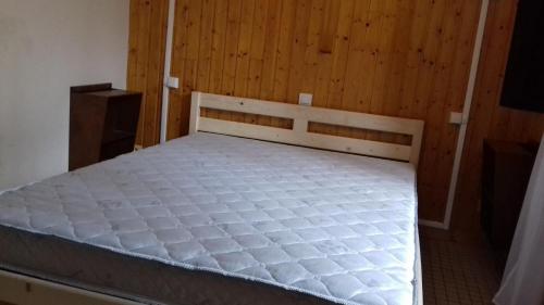 uma cama num quarto com uma parede de madeira em Les gîtes de la Planette - gîte 2 em Saint-Amans-Valtoret