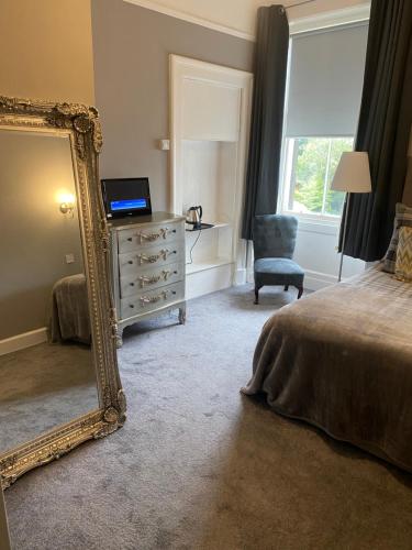 a bedroom with a mirror and a bed and a chair at Ellwyn House in Edinburgh