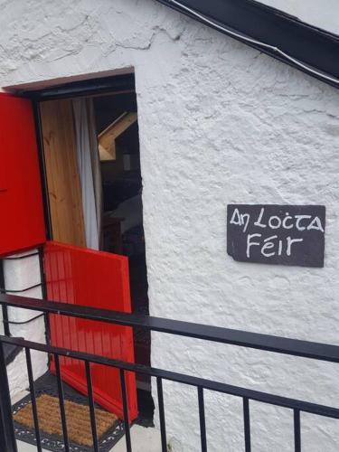 un panneau sur le côté d'un bâtiment avec une porte rouge dans l'établissement Quarvue Loft, à Ó Méith