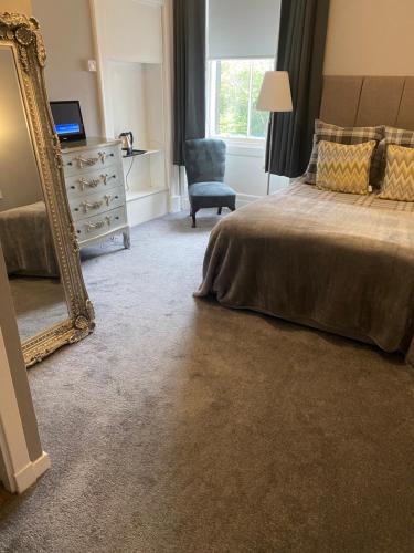 a bedroom with a bed and a mirror and a chair at Ellwyn House in Edinburgh