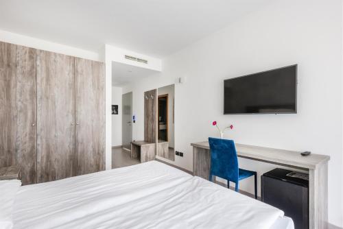 a bedroom with a bed and a desk with a tv at Hotel De Nac in Nago-Torbole