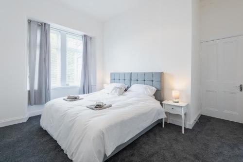 a white bedroom with a large white bed and a window at River View Apartment in Dundee