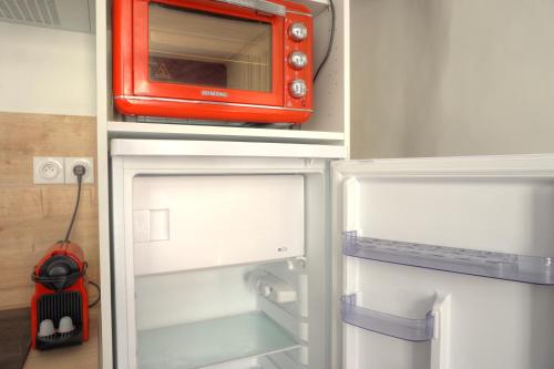 an orange microwave sitting on top of an open refrigerator at Studio au cœur du village provençale de Riez. Dans le Verdon. in Riez