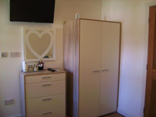a bedroom with a dresser and a large white cabinet at Brook Barn B&B in Hale