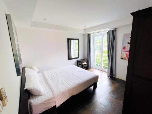 a bedroom with a white bed and a window at Kata Ocean View condominium by Lofty in Kata Beach