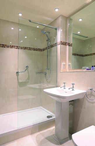 a bathroom with a sink and a shower with a glass door at Macdonald Kilhey Court Hotel in Wigan