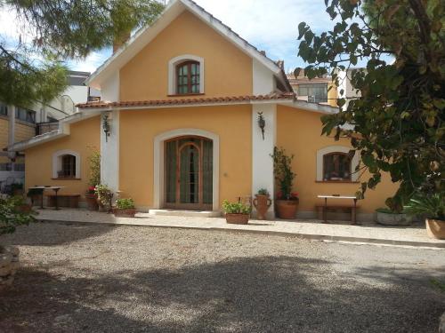 a yellow house with tables and benches in front of it at B&B Vecchia Suppenna in Andria