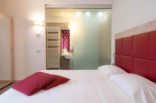 a bedroom with a large white bed with a red headboard at Albergo Monte Giove in Cadarese