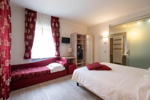 a bedroom with a bed and a couch and a window at Albergo Monte Giove in Cadarese
