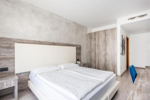 a bedroom with a white bed and a wooden wall at Hotel De Nac in Nago-Torbole