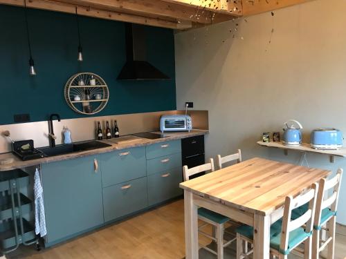 a kitchen with blue cabinets and a wooden table at Belladone Guest House theys Les 7 Laux in Theys