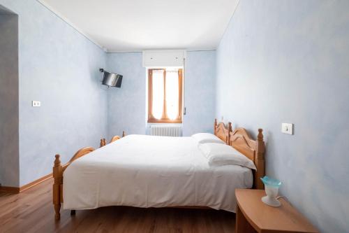 a bedroom with a white bed and a window at Albergo Monte Giove in Cadarese