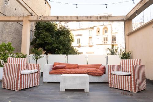 um pátio com 2 cadeiras e uma cama com lençóis laranja em Regina Margherita Suite em Nápoles