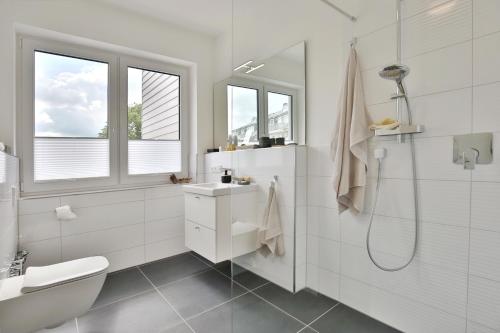 a white bathroom with a sink and a shower at Strandperle Ostsee Suite 3 in Niendorf