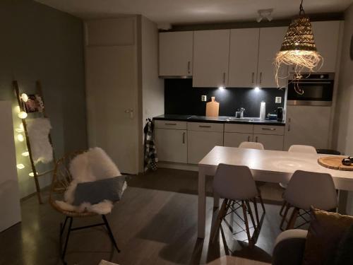 une cuisine avec une table et des chaises ainsi qu'une salle à manger dans l'établissement CallantsDuinzicht, Beachappartement 24, à Callantsoog