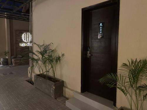 a black door with plants next to a building at Hamsun Shahrah-e-Faisal in Karachi